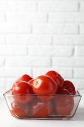Photo of Tasty pickled tomatoes in bowl on white table