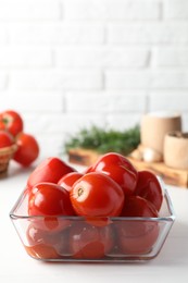 Tasty pickled tomatoes in bowl on white table