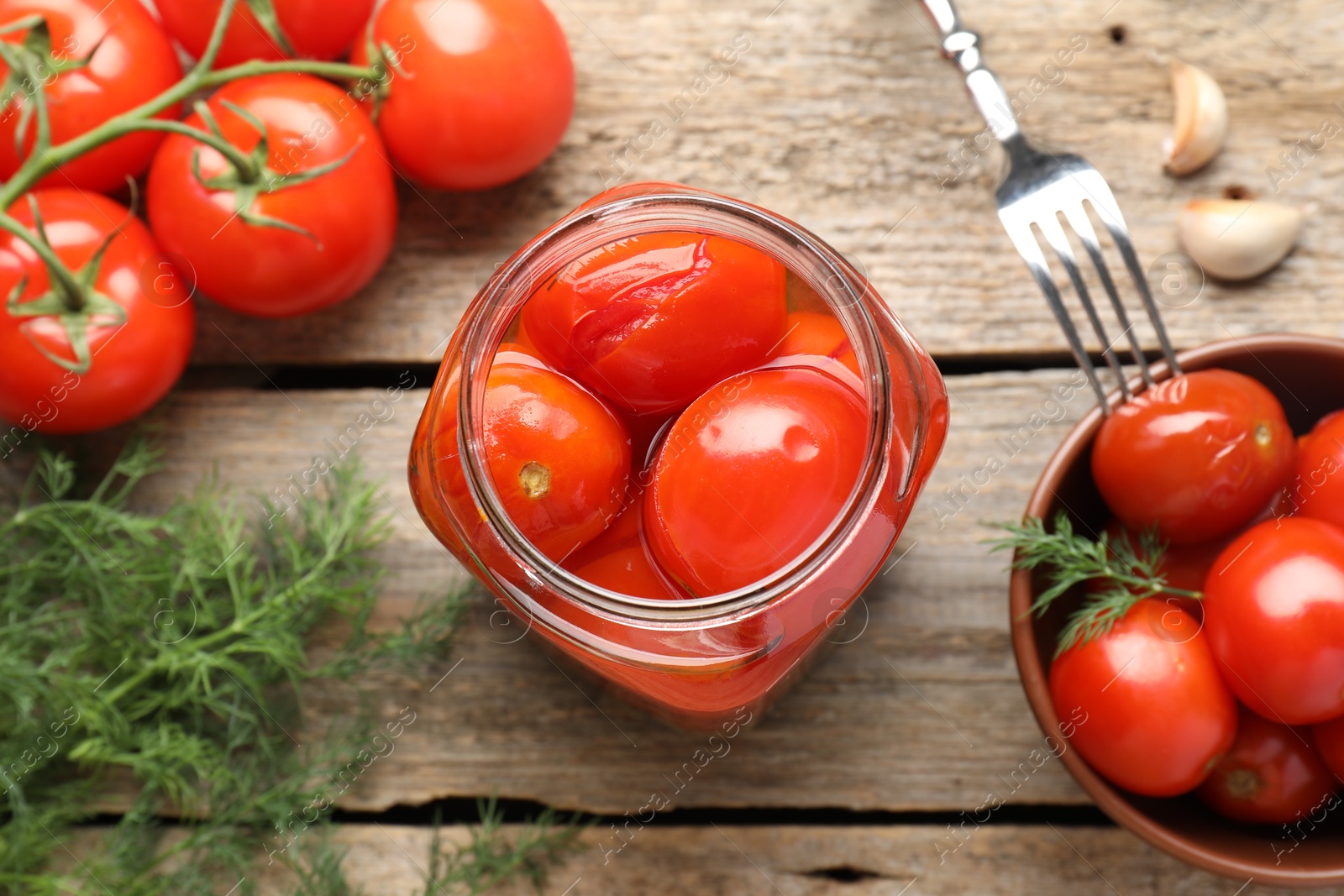 Photo of Tasty pickled tomatoes, spices, fresh vegetables and fork on wooden table, flat lay