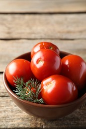 Photo of Tasty pickled tomatoes and dill in bowl on wooden table