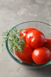 Tasty pickled tomatoes and dill in bowl on grey table