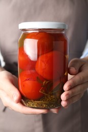 Photo of Woman holding jar with tasty pickled tomatoes, closeup