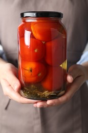 Woman holding jar with tasty pickled tomatoes, closeup