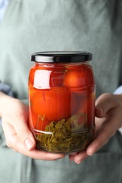 Woman holding jar with tasty pickled tomatoes, closeup