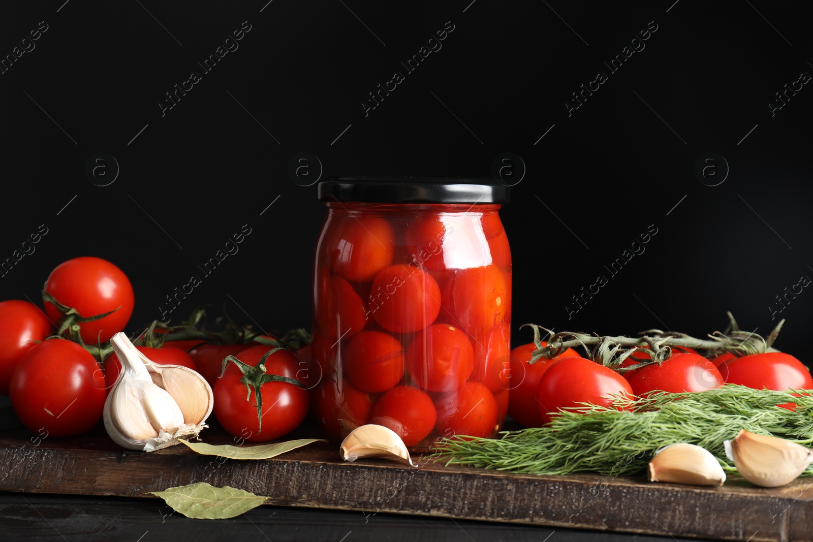 Photo of Tasty pickled tomatoes in jar, spices and fresh vegetables on wooden table
