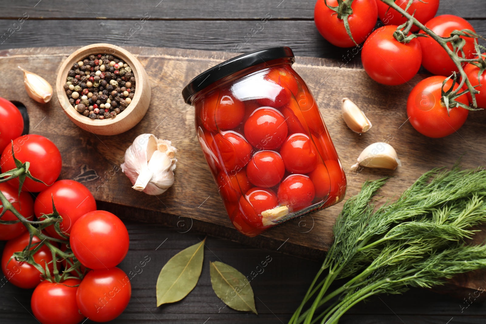 Photo of Tasty pickled tomatoes in jar, spices and fresh vegetables on grey wooden table, top view