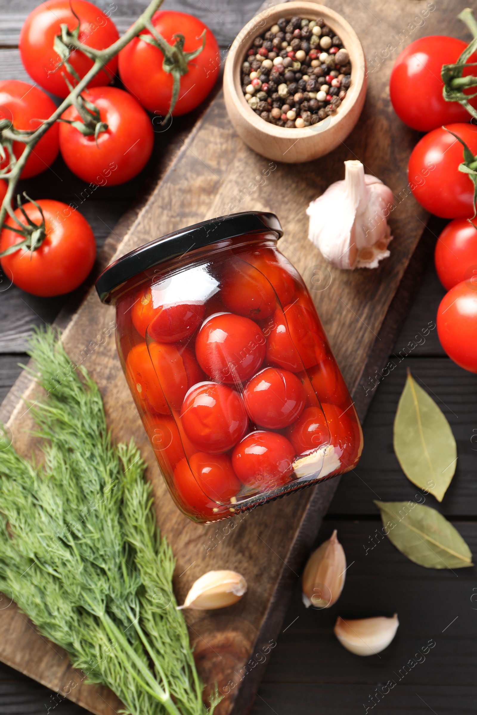 Photo of Tasty pickled tomatoes in jar, spices and fresh vegetables on grey wooden table, top view