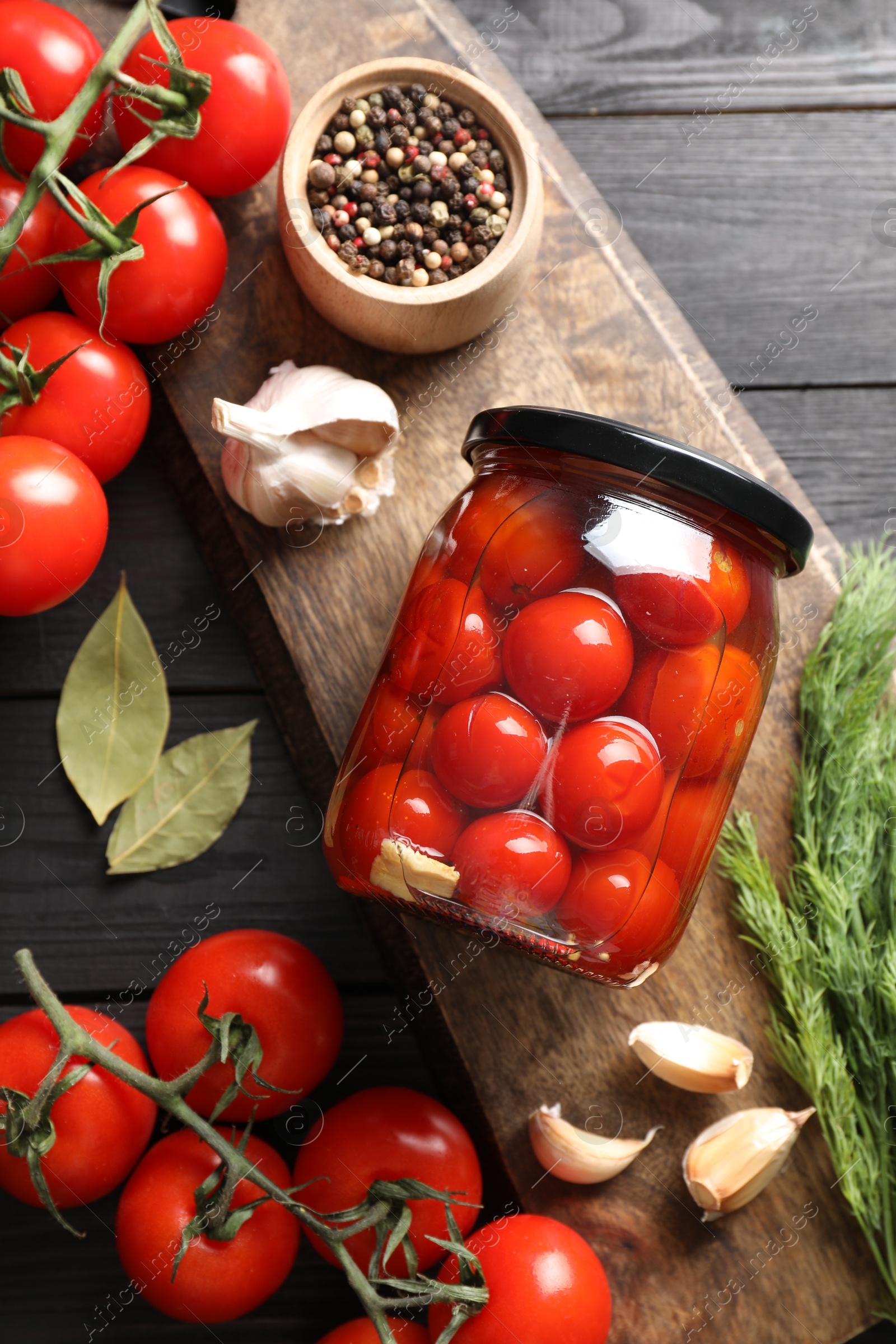 Photo of Tasty pickled tomatoes in jar, spices and fresh vegetables on grey wooden table, top view