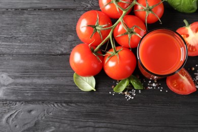 Tasty tomato juice in glass with fresh vegetables and spices on black wooden table, flat lay. Space for text