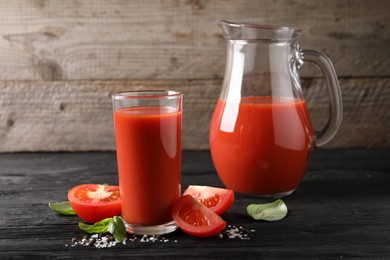 Photo of Tasty tomato juice with fresh vegetables and spices on black wooden table