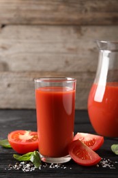 Photo of Tasty tomato juice with fresh vegetables and spices on black wooden table