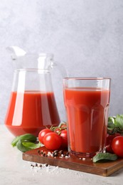 Photo of Tasty tomato juice with spices and fresh vegetables on light table