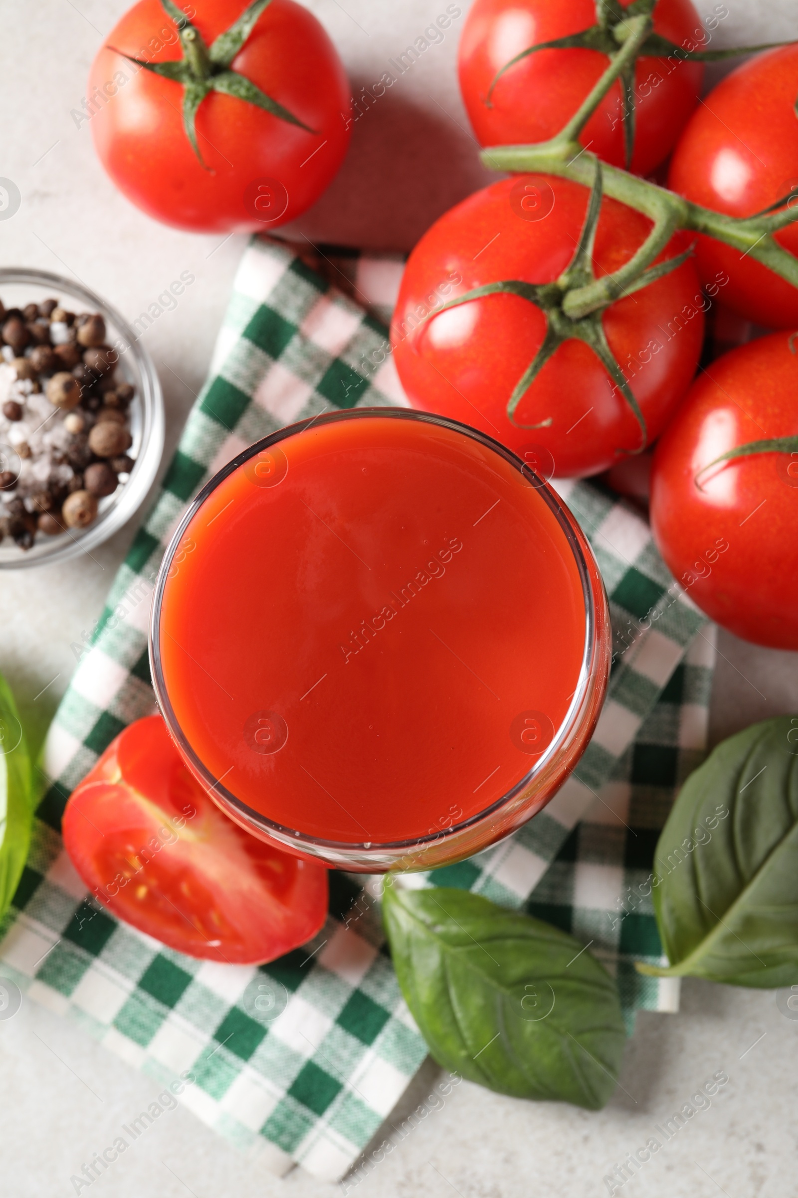 Photo of Tasty tomato juice in glass, spices and fresh vegetables on light table, flat lay