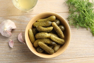 Photo of Pickled cucumbers in bowl, dill, garlic and brine on wooden table, flat lay