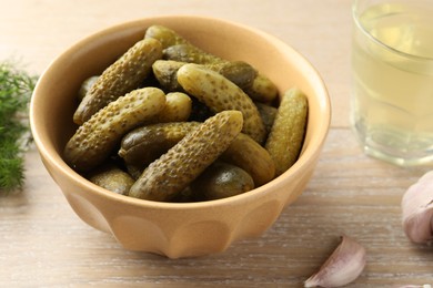 Pickled cucumbers in bowl on wooden table, closeup