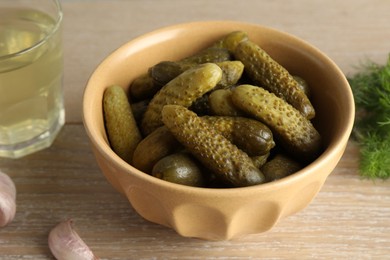 Photo of Pickled cucumbers in bowl on wooden table, closeup