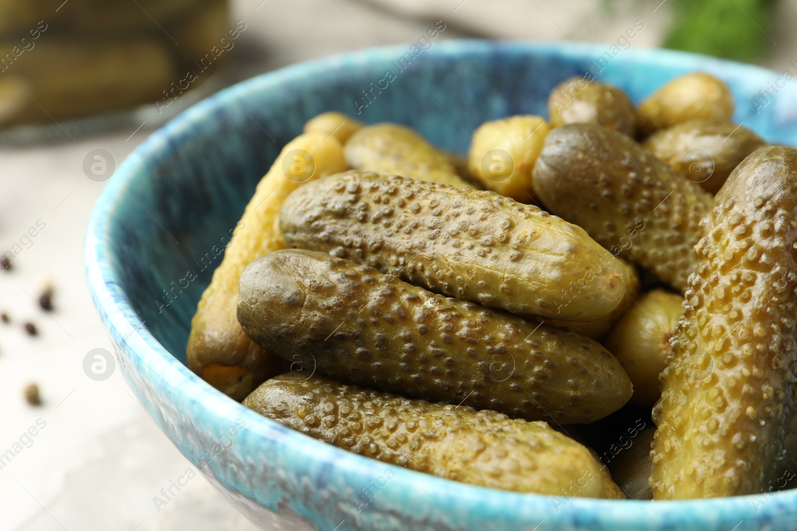 Photo of Pickled cucumbers in bowl on grey table, closeup