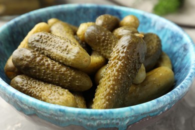 Pickled cucumbers in bowl on grey table, closeup
