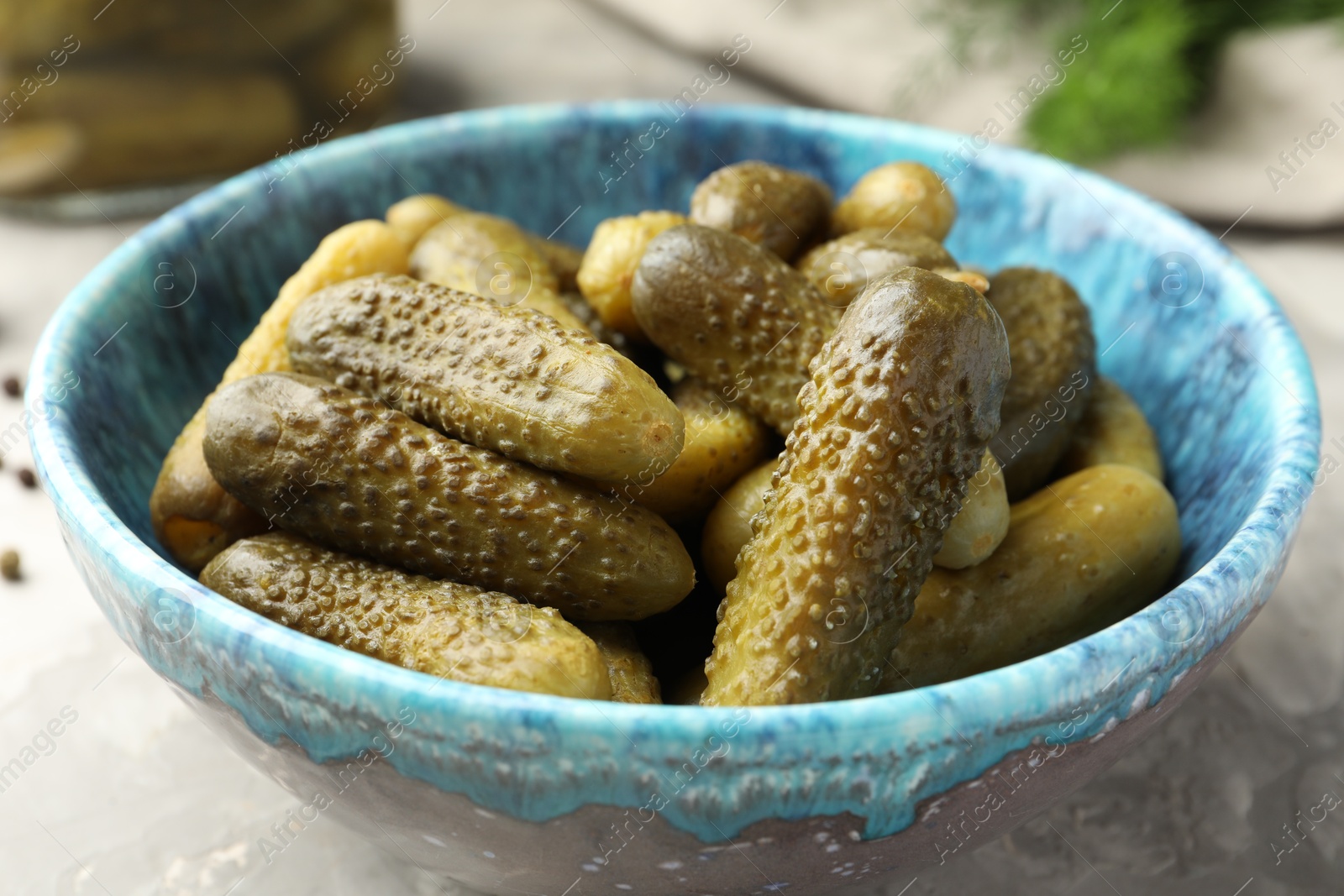 Photo of Pickled cucumbers in bowl on grey table, closeup