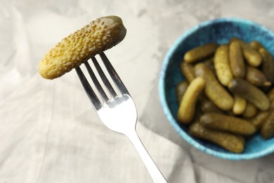 Fork with pickled cucumber and bowl full of ones on table, top view