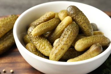 Pickled cucumbers in bowl on wooden table, closeup