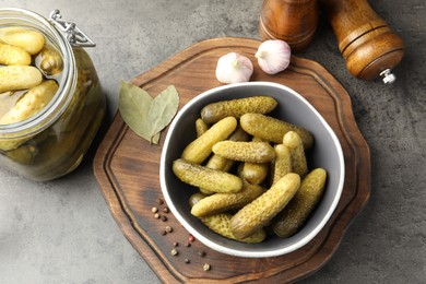 Photo of Pickled cucumbers in bowl, jar and spices on grey textured table, flat lay