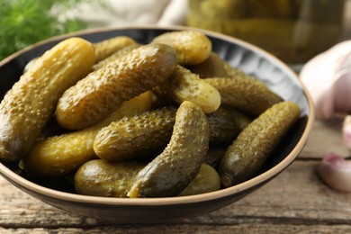 Photo of Pickled cucumbers in bowl on wooden table, closeup