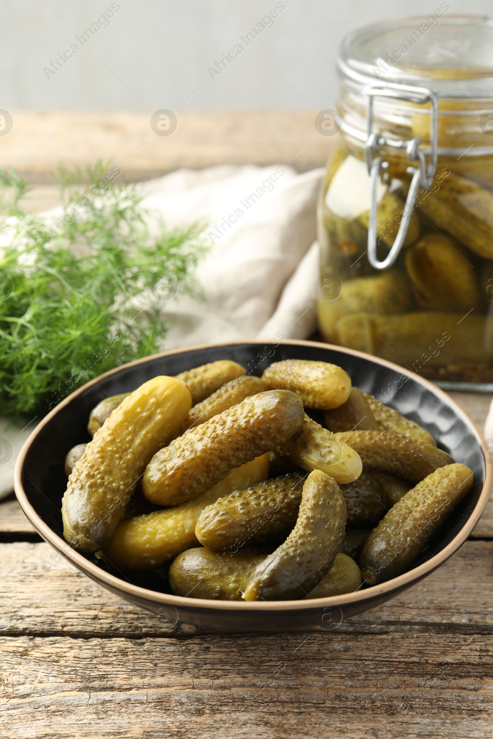 Photo of Pickled cucumbers in bowl on wooden table