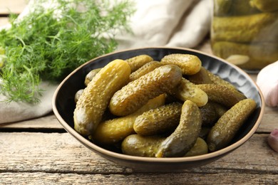 Photo of Pickled cucumbers in bowl on wooden table, closeup