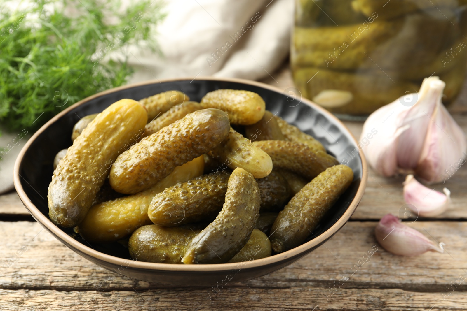 Photo of Pickled cucumbers in bowl on wooden table, closeup