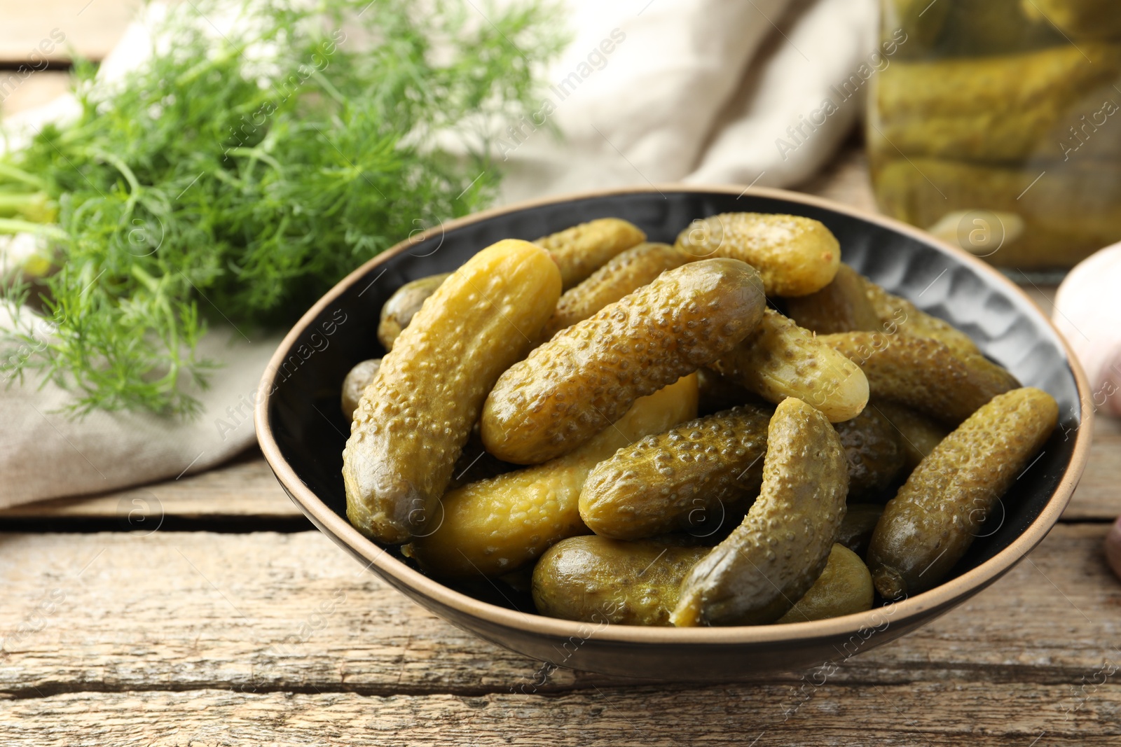 Photo of Pickled cucumbers in bowl on wooden table, closeup