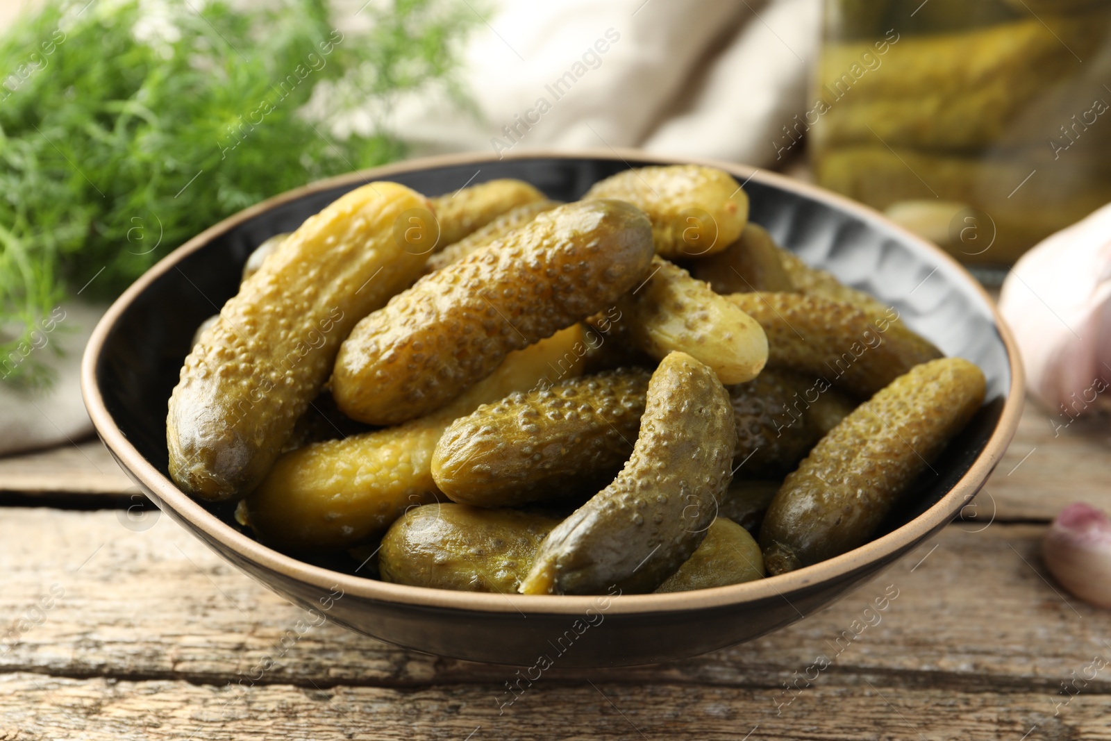 Photo of Pickled cucumbers in bowl on wooden table, closeup