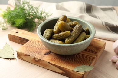 Pickled cucumbers in bowl on wooden table