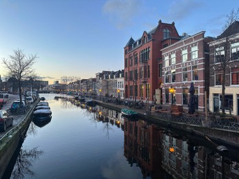 Photo of Beautiful view of canal with moored boats in city under blue sky