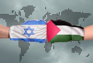 Image of Political conflict. Men in boxing gloves with flags of Israel and Palestine fighting against world map, closeup