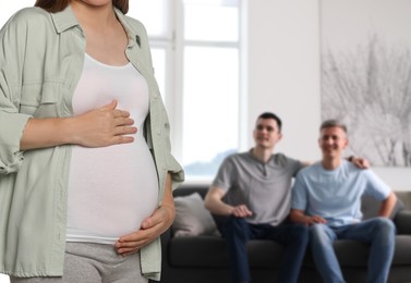 Image of Pregnant surrogate mother and happy gay couple at home, selective focus