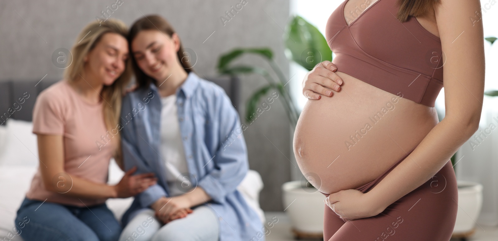 Image of Pregnant surrogate mother and happy lesbian couple at home, selective focus