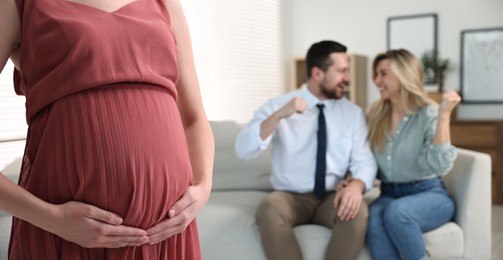 Pregnant surrogate mother and happy couple at home, selective focus