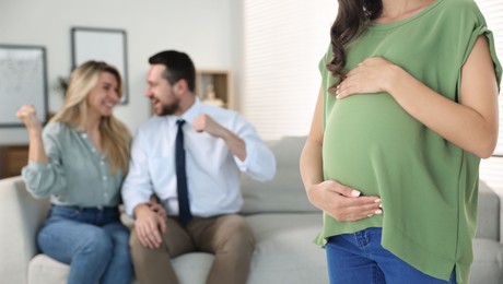 Pregnant surrogate mother and happy couple at home, selective focus