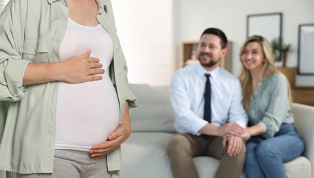 Pregnant surrogate mother and happy couple at home, selective focus