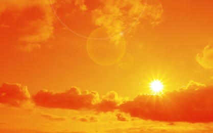 Image of Orange sky with sun and clouds during hot summer weather