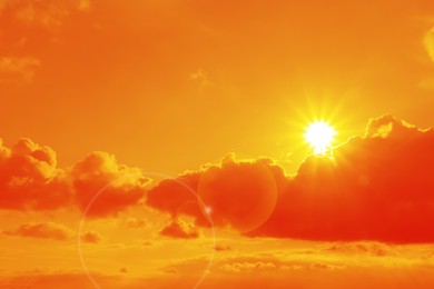Image of Orange sky with sun and clouds during hot summer weather