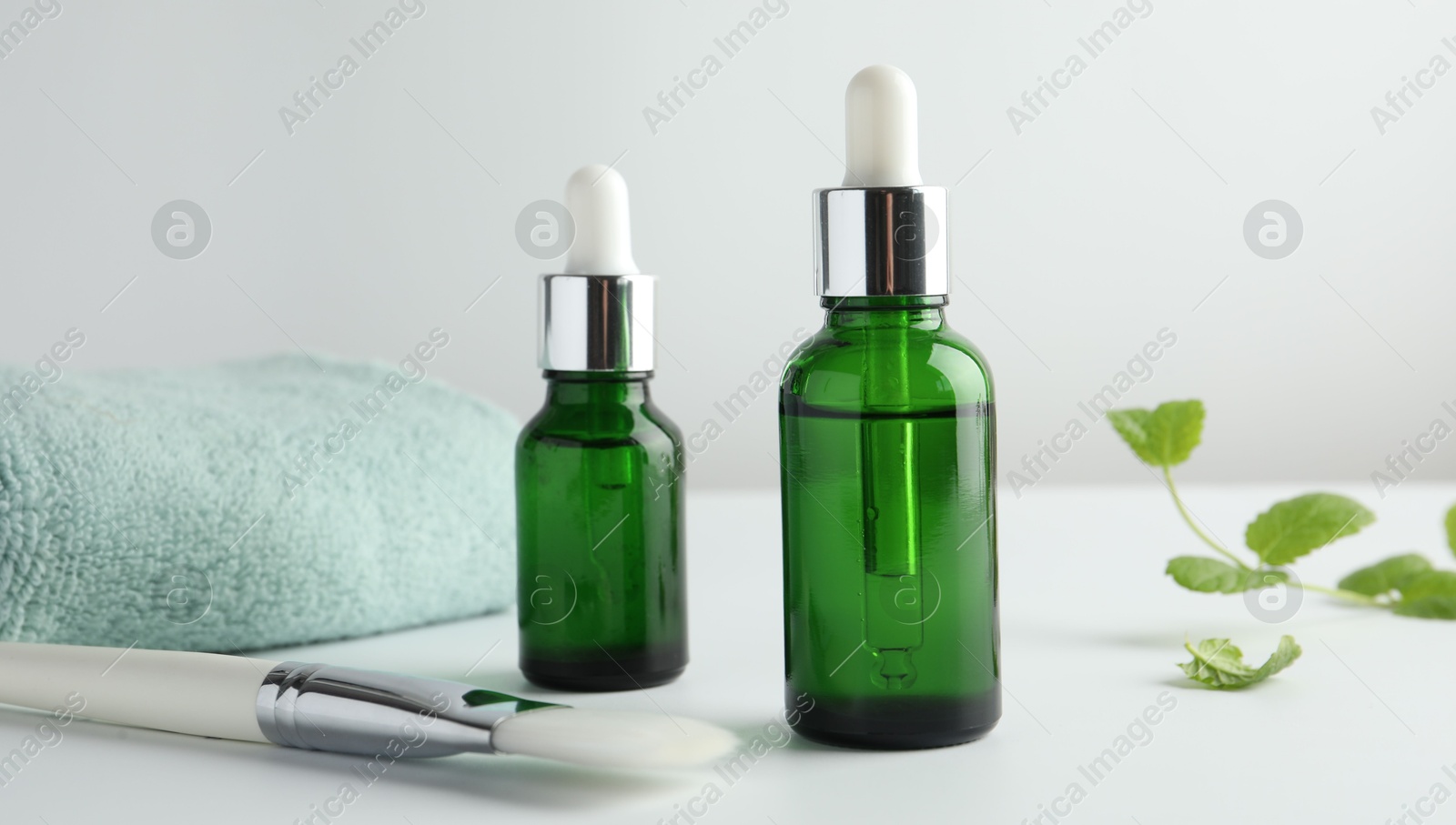 Photo of Bottles of chemical peel, towel and brush on light background, closeup. Peeling procedure