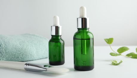 Photo of Bottles of chemical peel, towel and brush on light background, closeup. Peeling procedure