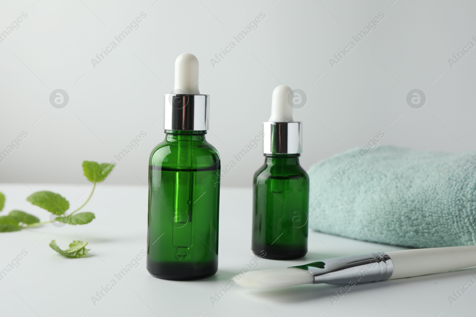 Photo of Bottles of chemical peel, towel and brush on light background. Peeling procedure