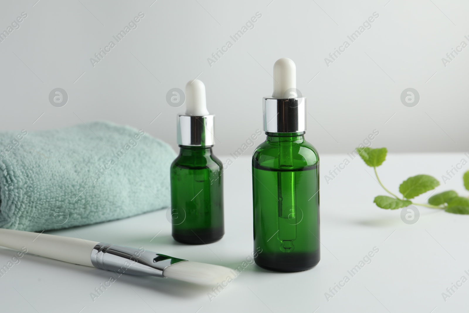 Photo of Bottles of chemical peel, towel and brush on light background. Peeling procedure