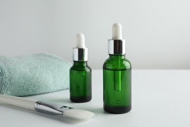 Photo of Bottles of chemical peel, towel and brush on light background. Peeling procedure