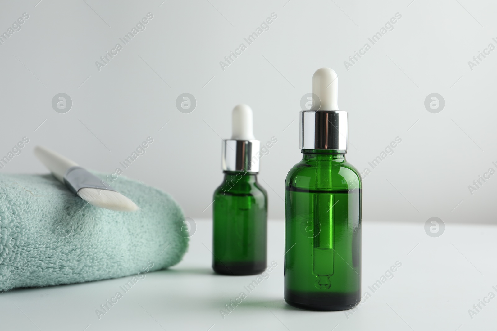 Photo of Bottles of chemical peel, towel and brush on light background. Peeling procedure