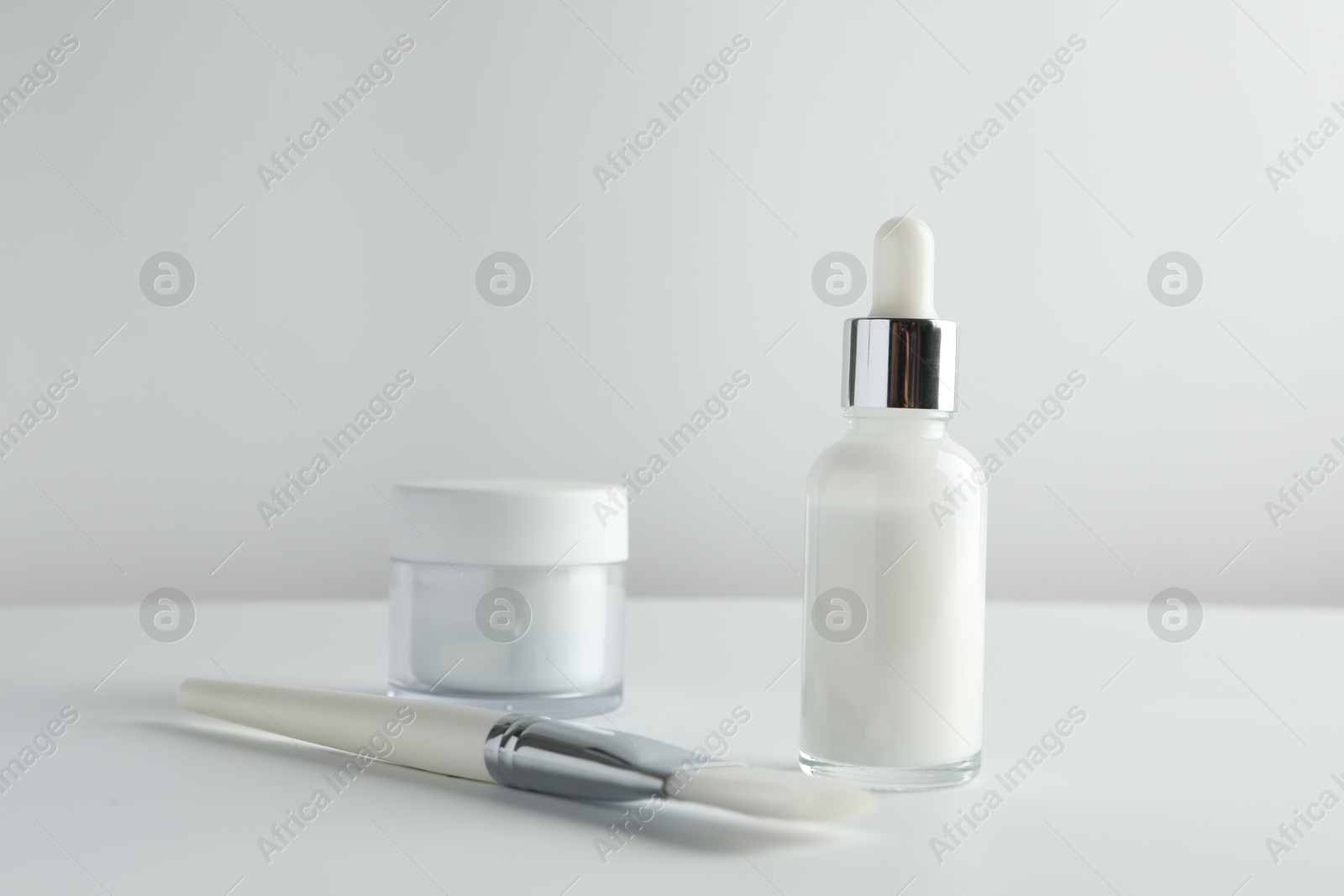 Photo of Bottle of chemical peel liquid, jar and brush on light background. Peeling procedure