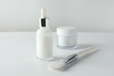 Bottle of chemical peel liquid, jar and brush on light background. Peeling procedure